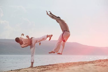 Erkekler capoeira sahilde - kavramı kişi, yaşam tarzı ve spor hakkında eğitmek. Eğitim iki savaşçıları