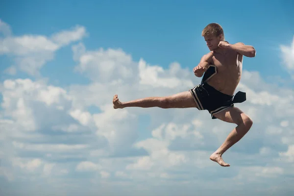 Man flying kick in sky background. Martial arts composition