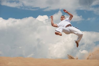 Genç bir adam capoeira gökyüzüne karşı eğitiyor. Kişi, yaşam tarzı ve spor kavramı. Bir adam bir tekme atlamak gerçekleştirir.