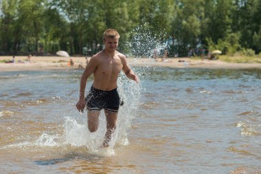 Genç bir adam sahilde eğitim. Sabah koşuya temiz havada bir genç adam