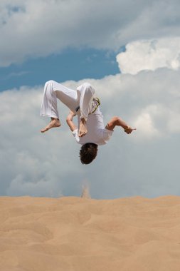 Acrobat akrobatik bir hüner, takla sahilde gerçekleştirir. Adam trenler capoeira