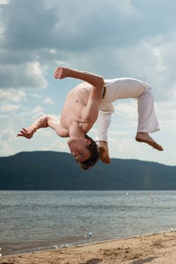 Acrobat akrobatik bir hüner, takla sahilde gerçekleştirir. Adam trenler capoeira
