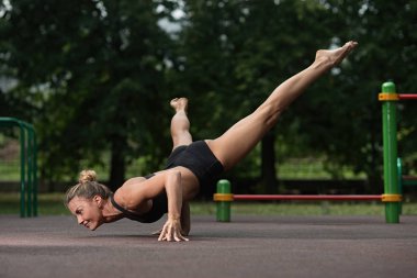 Spor akrobasi kız ellerinin üzerinde duruyor ve eğitim alanı akrobatik bir öğede yapar
