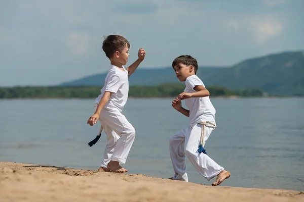 Sahilde deniz üzerinde iki çocuk eğitim: capoeira, spor