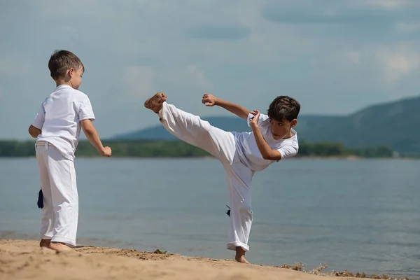 Sahilde deniz üzerinde iki çocuk eğitim: capoeira, spor