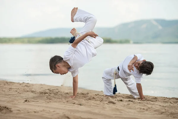 Sahilde deniz üzerinde iki çocuk eğitim: capoeira, spor