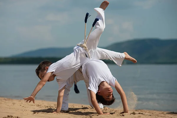 Sahilde deniz üzerinde iki çocuk eğitim: capoeira, spor
