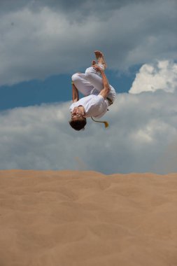 Acrobat akrobatik bir hüner, takla sahilde gerçekleştirir. Adam trenler capoeira