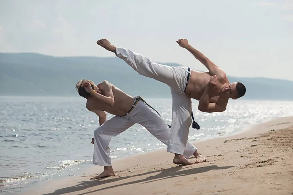 Erkekler capoeira sahilde - kavramı kişi, yaşam tarzı ve spor hakkında eğitmek. Eğitim iki savaşçıları