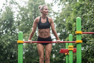 kız açık havada yatay çubuğu'nda yapıyor. Kadın olarak çalışma yapmaktadır