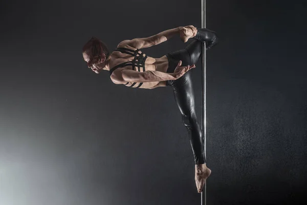 Man with pylon. Male pole dancer dancing on a black background. Strong and graceful Guy dancing in smoke