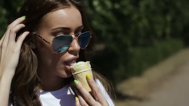 Νεαρό κορίτσι τρώει παγωτό σε εξωτερικούς χώρους το καλοκαίρι, στη ζέστη — Αρχείο Βίντεο