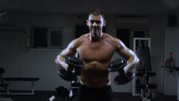 Muscular man in the gym training with dumbbells, guy pumps his deltoid muscle — Stock Video