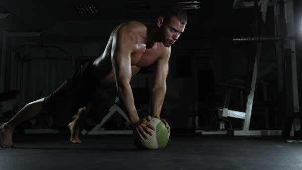 Ung muskulös man gör gymnastik i gymmet med boll — Stockvideo