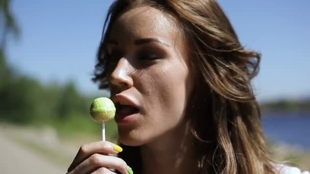 Mooi meisje zuigt Lollipop in de zomer buiten — Stockvideo