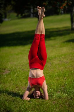 Pratik yoga açık havada genç çekici kadın. Kız baş aşağı bir hareketten gerçekleştirir. Spor, yoga, fitness ve sağlık kavramı