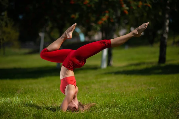 Pratik yoga açık havada genç çekici kadın. Kız baş aşağı bir hareketten gerçekleştirir. Spor, yoga, fitness ve sağlık kavramı