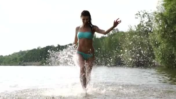 Chica corriendo en el agua en el mar, divertirse, salpicaduras en los lados — Vídeo de stock