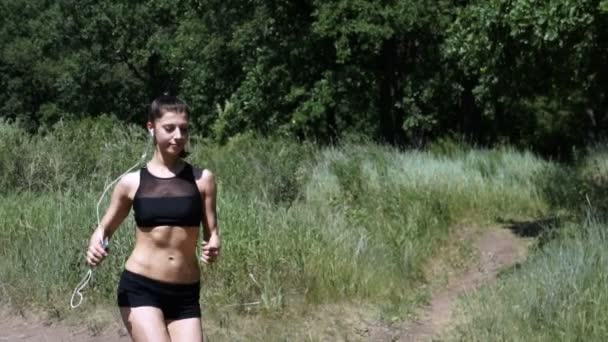 Una joven corriendo por el bosque. La chica se dedica a los deportes . — Vídeos de Stock