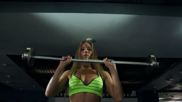 Hermosa chica joven atlética muscular sexy. Chica de fitness entrena, haciendo ejercicios con una barra — Vídeo de stock