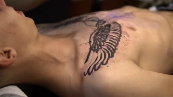 Καλλιτέχνης αντλεί ένα τατουάζ στο στήθος του ένα close-up άνθρωπος — Αρχείο Βίντεο