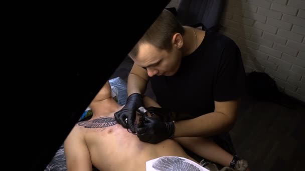 Konstnären drar en tatuering på bröstet av en man i studion — Stockvideo