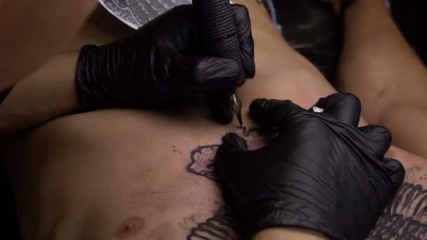 Konstnären drar en tatuering på bröstet av en man-närbild — Stockvideo