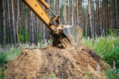 Bir kova ile yere kazı ekskavatör Kazı çalışmaları gerçekleştirir