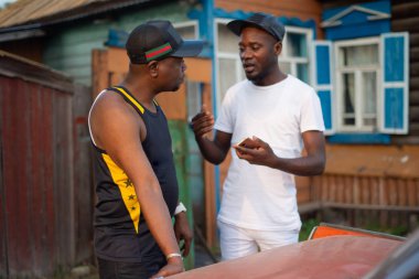 İki zenci iş konularında bir köy evinin arka plan üzerinde tartışmak.