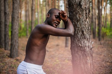 Afrika kökenli Amerikalı yakınındaki ormanda bir ağaç poz gömleksiz