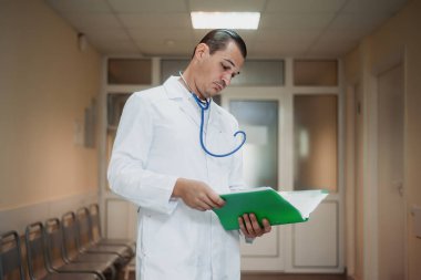 Genç erkek doktor hastane bir klasöre bakarak