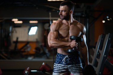 Dambıl ile egzersiz kas yakışıklı genç. Adam onun pazı trenler