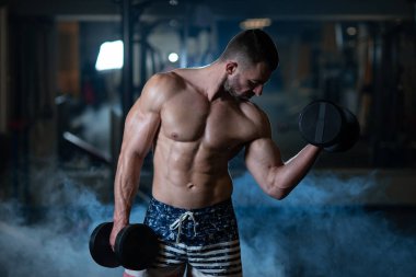 Dambıl ile egzersiz kas yakışıklı genç. Adam onun pazı trenler