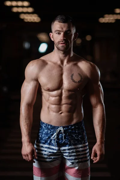 筋肉ボディを持つ残忍なアスレチック男ポーズ ジムで彼の筋肉を披露します 健康的なライフ スタイルのコンセプト — ストック写真