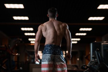 Kas vücut uzak gösterilen spor salonunda poz ile acımasız atletik adam. Sağlıklı bir yaşam tarzı kavramı