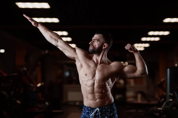 一个肌肉发达的野蛮人在健身房里摆姿势 露出他的二头肌 健康生活方式的概念 — 图库照片