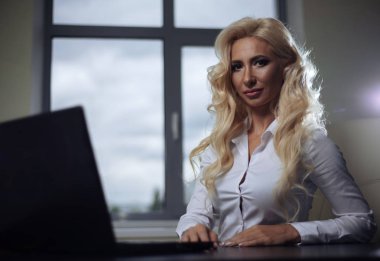 çekici kadın patron ofiste bir masada oturan