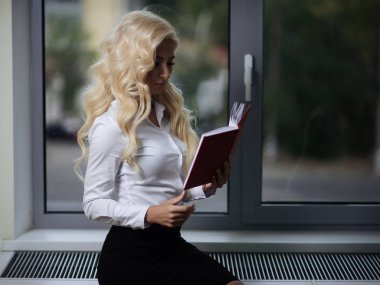 ofiste çekici çalışan raporları penceresi yakınındaki bir kitap onun elinde tutan okur