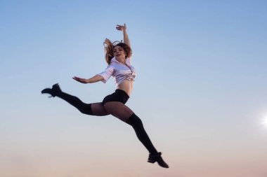 Ponpon ponpon kızla akrobatik öğe açık havada gökyüzüne karşı çatıda gerçekleştirir