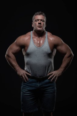 Güçlü kas vücut geliştirmeci siyah bir arka plan üzerinde poz. Güç ve sağlık kavramı