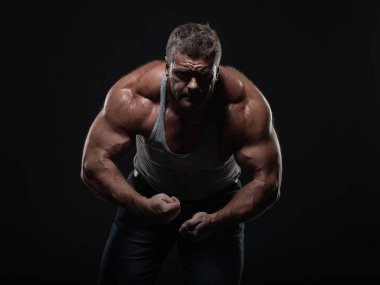 Güçlü kas vücut geliştirmeci siyah bir arka plan üzerinde poz. Güç ve sağlık kavramı