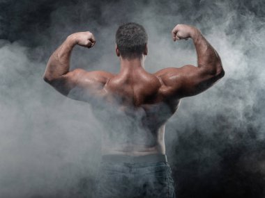 Güçlü bir kas adam pazı siyah bir arka plan üzerinde gösterir. Güç ve fitness kavramı