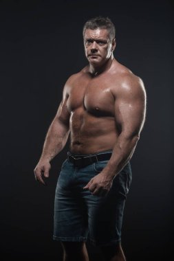 Güçlü kas vücut geliştirmeci siyah bir arka plan üzerinde poz. Güç ve sağlık kavramı