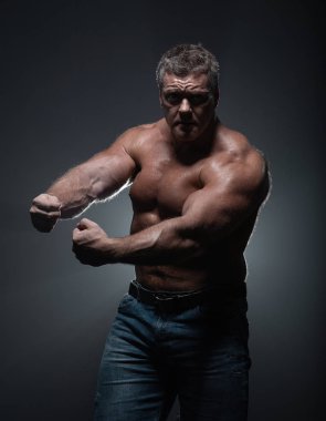 Güçlü kas vücut geliştirmeci siyah bir arka plan üzerinde poz. Güç ve sağlık kavramı