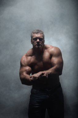 Güçlü kas vücut geliştirmeci siyah bir arka plan üzerinde poz. Güç ve duman sağlık kavramı