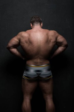 Güçlü kas atlet sırtı siyah grunge duvarının yakınında kapalı gösterir