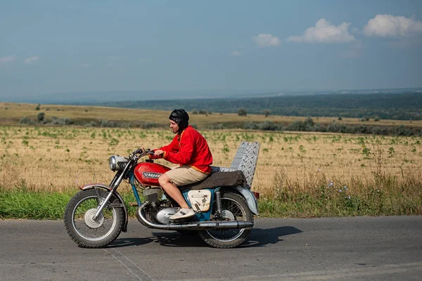 Rusya, Syzran - 2 Eylül 2018: Güzel bir manzara arka plan üzerine karayolu üzerinde eski bir Sovyet motosiklet üzerinde Rus genç motosikletçi rides