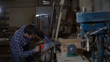 yetişkin adam atölye mengeneye sabitlenmiş bir ahşap tahta testereleri
