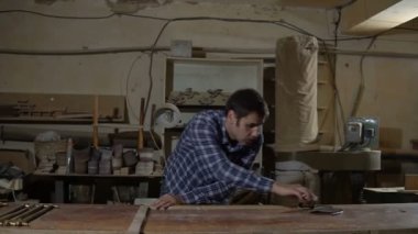 İşçi iş elbisesi bir tezgah üzerinde uzun sarı cetvel ile ahşap tahta ölçer