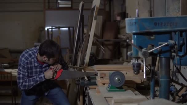 Uomo adulto sega una tavola di legno, bloccata in un vizio, in officina — Video Stock